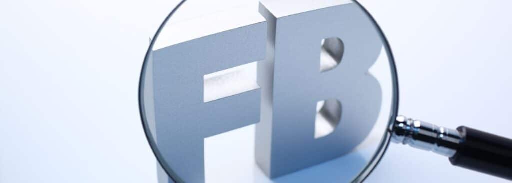 Close-up of a magnifying glass over a large blue 3D 'FB' letters logo