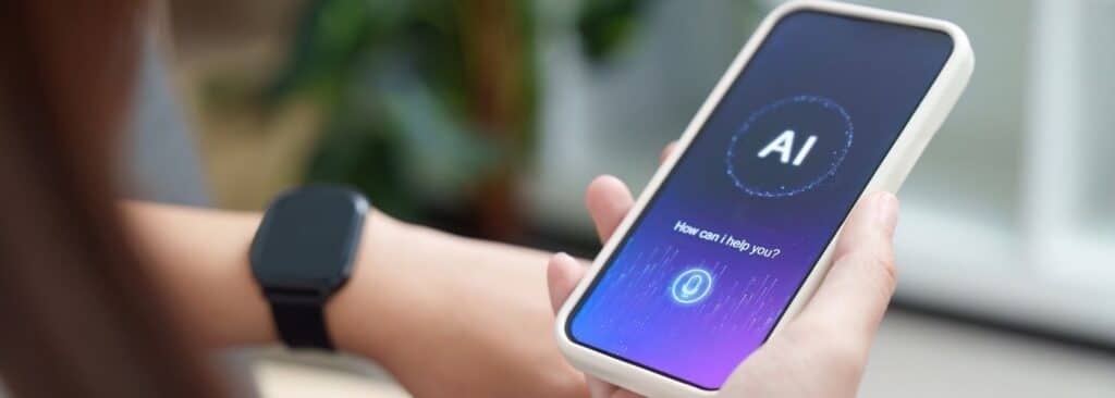Person holds a smartphone displaying an AI assistant interface; wearable smartwatch is visible on their wrist.