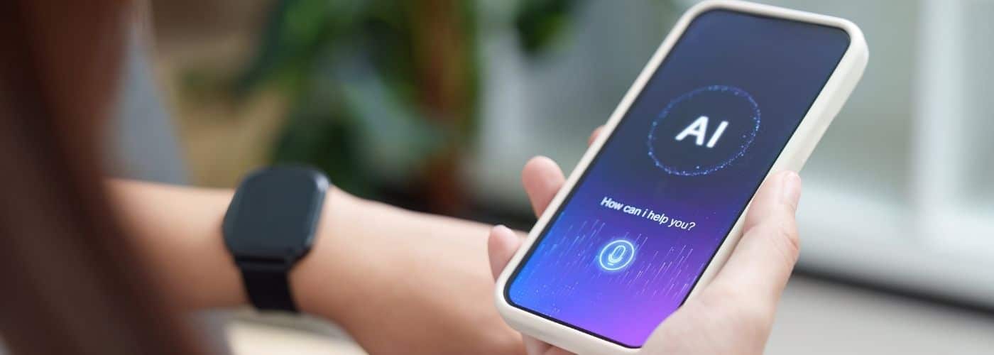 Person holds a smartphone displaying an AI assistant interface; wearable smartwatch is visible on their wrist.